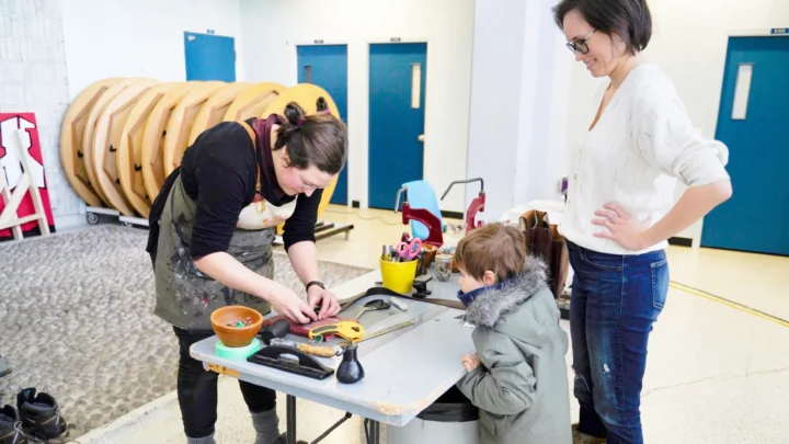 Une mère et son fils qui regarde une personne réparer un appareil dans le puits du Hall