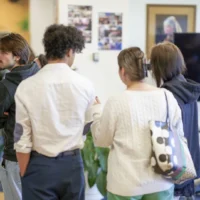 Des gens qui assistent à un exposition d'un projet en photographie à la bibliothèque